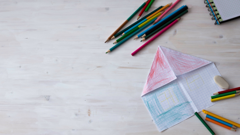 Colored pencils and a paper airplane strewn across a white table to inspire happiness when thinking about how to start homeschooling.